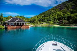 a boat in the water next to a house on a lake at Hilton Seychelles Labriz Resort & Spa in Silhouette Island