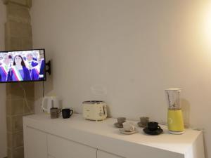 une télévision assise sur un mur au-dessus d'un comptoir blanc avec un appareil dans l'établissement Apartment Spicchi di Salento-1 by Interhome, à Vernole