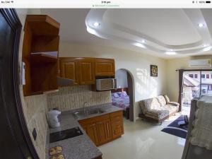 a kitchen with wooden cabinets and a living room at Junior Apartment in Pattaya