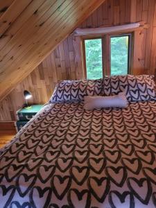a large bed in a room with a wooden ceiling at Le petit chalet sur le lac in Sainte-Marguerite