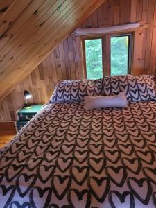 Cette chambre comprend un grand lit et un plafond en bois. dans l'établissement Le petit chalet sur le lac, à Sainte-Marguerite