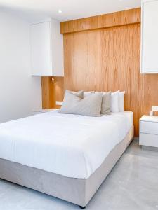 a bedroom with a large white bed with wooden walls at Phaedrus Living: Marina Sea View Flat 214 Gold in Paphos