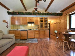 cocina con armarios de madera, mesa y sofá en Apartment Isola di Madesimo Apartments-1 by Interhome en Isola