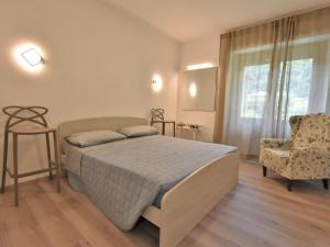 1 dormitorio con 1 cama, 1 silla y 1 ventana en Apartment La Casa di Lara by Interhome, en Morbegno