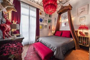 a bedroom with a canopy bed with red sheets and a window at Les Petites Suites Dieppoises - La Demeure de Peau d'Ane in Dieppe