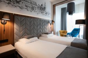 a hotel room with two beds and a blue chair at Garden Square Hotel in Kraków