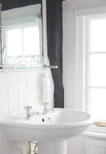 a white sink in a bathroom with two windows at The Bell Hotel Woburn By Greene King Inns in Woburn