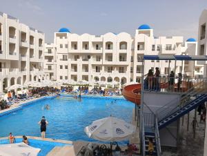 uma grande piscina em frente a um grande edifício em شاليه الزمردة بمنتجع سانتوريني em El Alamein