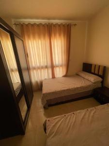 um pequeno quarto com uma cama e uma janela em شاليه الزمردة بمنتجع سانتوريني em El Alamein