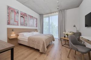 Un dormitorio con cama, escritorio y televisión. en PIEKARNIA Żywa Kultura Atmospheric Apartments in Wrocław by Noclegi Renters, en Wroclaw