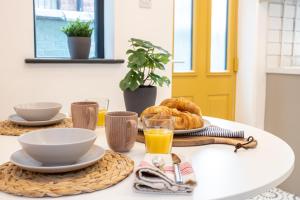 a table with a breakfast of orange juice and croissants at Stunning Scandi Abode in Manchester Parking in Manchester