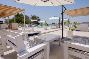 un groupe de tables avec des parasols et une piscine dans l'établissement Villa Chiara, à Lecce