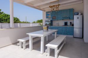 une cuisine avec des armoires bleues, une table blanche et des bancs dans l'établissement Villa Chiara, à Lecce