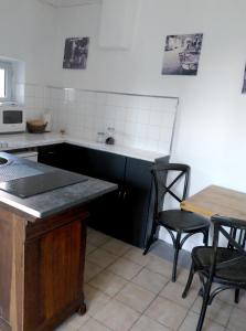 a kitchen with a counter and chairs and a table at Le grenier d'Emma in Langeac