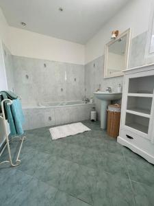 La salle de bains est pourvue d'une baignoire, d'un lavabo et d'un miroir. dans l'établissement Villa individuelle - CHASSIEU, à Chassieu