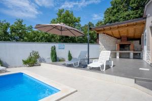 a swimming pool with two chairs and an umbrella at Houses Trinetta in Valtura