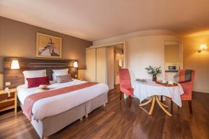 リュクスイユ・レ・バンにあるHOTEL CERISE - LES SOURCES Luxeuil-les-Bainsのベッド、テーブル、椅子が備わるホテルルームです。