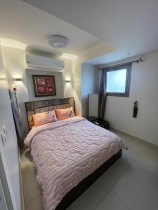 a bedroom with a bed with pink sheets and a window at Marrassi Marina spacious chalet in El Alamein