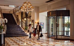 un hombre, una mujer y un niño caminando por un vestíbulo en Fairmont Le Montreux Palace, en Montreux