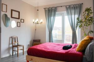 a bedroom with a red bed and a window at Aquarela do Tejo Guesthouse in Vila Franca de Xira