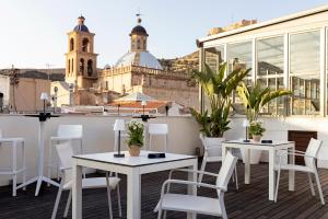 a balcony with tables and chairs and a view of a city at Hospes Amérigo, Alicante, a Member of Design Hotels in Alicante