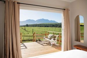 Schlafzimmer mit Balkon und Blick auf ein Feld in der Unterkunft Melkhout River Cottage in Bonnievale