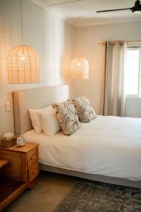 Schlafzimmer mit einem Bett mit weißer Bettwäsche und Kissen in der Unterkunft Melkhout River Cottage in Bonnievale