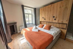 a bedroom with a bed with an orange blanket at La Tannerie de Durbuy Guesthouse in Durbuy