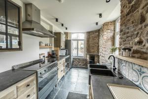 a large kitchen with a stone wall and stainless steel appliances at La Tannerie de Durbuy Guesthouse in Durbuy