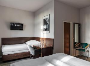 ein Hotelzimmer mit 2 Betten, einem Schreibtisch und einem TV in der Unterkunft Hotel Nova in Berlin