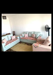 a living room with two couches and pink pillows at Amwaj north Coast 