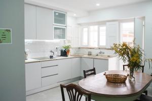 uma cozinha com armários brancos e uma mesa com um cesto em Aquarela do Tejo Guesthouse em Vila Franca de Xira