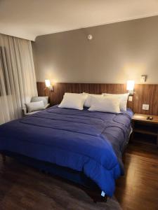 1 dormitorio con 1 cama grande con sábanas y almohadas azules en Suíte 5 estrelas Hotel Av Ibirapuera 2534 Piscina, en São Paulo