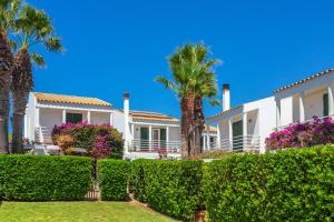 a white house with palm trees and bushes at Aloes in Sa Caleta