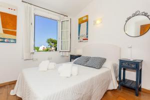 a white bedroom with a bed and a window at Aloes in Sa Caleta