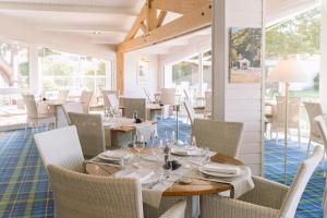 een eetkamer met tafels, stoelen en ramen bij Fleur de Sel in Noirmoutier-en-l'lle