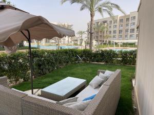 a patio with a couch and an umbrella and a lawn at Marrassi Marina spacious chalet in El Alamein