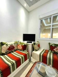 ein Wohnzimmer mit einem Sofa und einem TV in der Unterkunft Appartement dans résidence à 2 pas de la mer et parking in Tangier