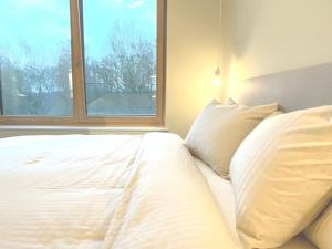 a white bed with two pillows and a window at Kirchberg Apartment - High End 1 bedroom Apartment with terrace & parking in Luxembourg