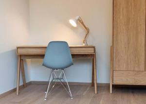 une chaise bleue assise à côté d'un bureau avec une lampe dans l'établissement Kirchberg Apartment - High End 1 bedroom Apartment with terrace & parking, à Luxembourg