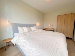 ein Schlafzimmer mit einem großen weißen Bett und einem Holzschrank in der Unterkunft Kirchberg Apartment - High End 1 bedroom Apartment with terrace & parking in Luxemburg (Stadt)