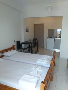 two beds in a room with a kitchen and a table at Golden Beach-Tsianis Apartments in Nea Mesangala