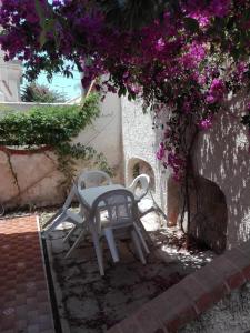 una mesa y sillas sentadas bajo un árbol con flores púrpuras en Sapore di Mare, en Marina di Noto