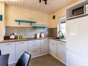 a kitchen with white cabinets and a white refrigerator at Domki Poczekajka in Sasino