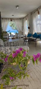 uma sala de estar com flores roxas no meio em Villa in spiaggia tra fiori e mare em Torre Mileto