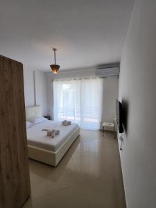 ein weißes Schlafzimmer mit einem Bett und einem TV in der Unterkunft Ioli's House in Mullini i Danit