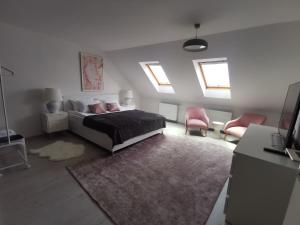 a bedroom with a bed and two pink chairs at Casa Good Vibes in Târgu-Mureş