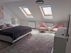 a bedroom with a bed and two pink chairs at Casa Good Vibes in Târgu-Mureş