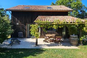 une pergola avec une table et des chaises devant une maison dans l'établissement Au séchoir à Tabac, à Bergerac