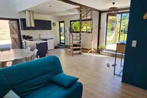 a living room with a blue couch and a kitchen at Au séchoir à Tabac in Bergerac